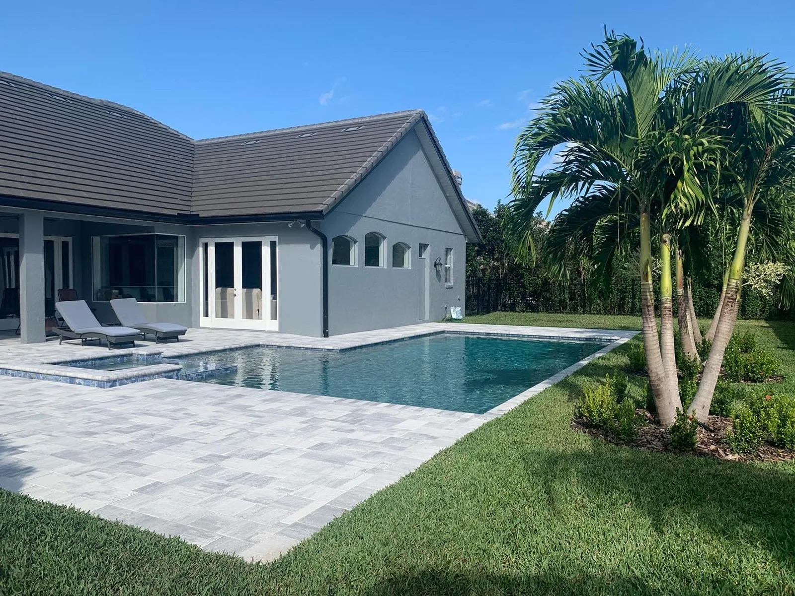 Custom rectangular pool with travertine paver deck and mature palm landscaping — Central Florida build