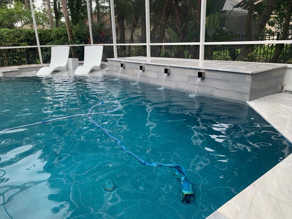 Renovated pool with modern scupper wall and white in-pool loungers