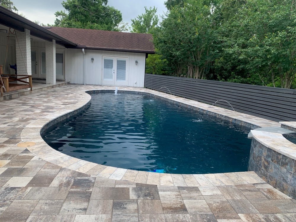 Pool resurfaced to dark navy water with travertine deck and modern slat fence