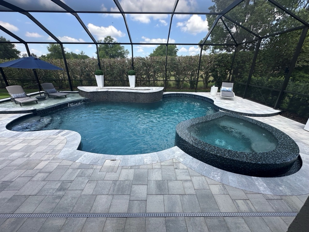 Fully reshaped pool with black glass-tile raised spa and grey paver deck