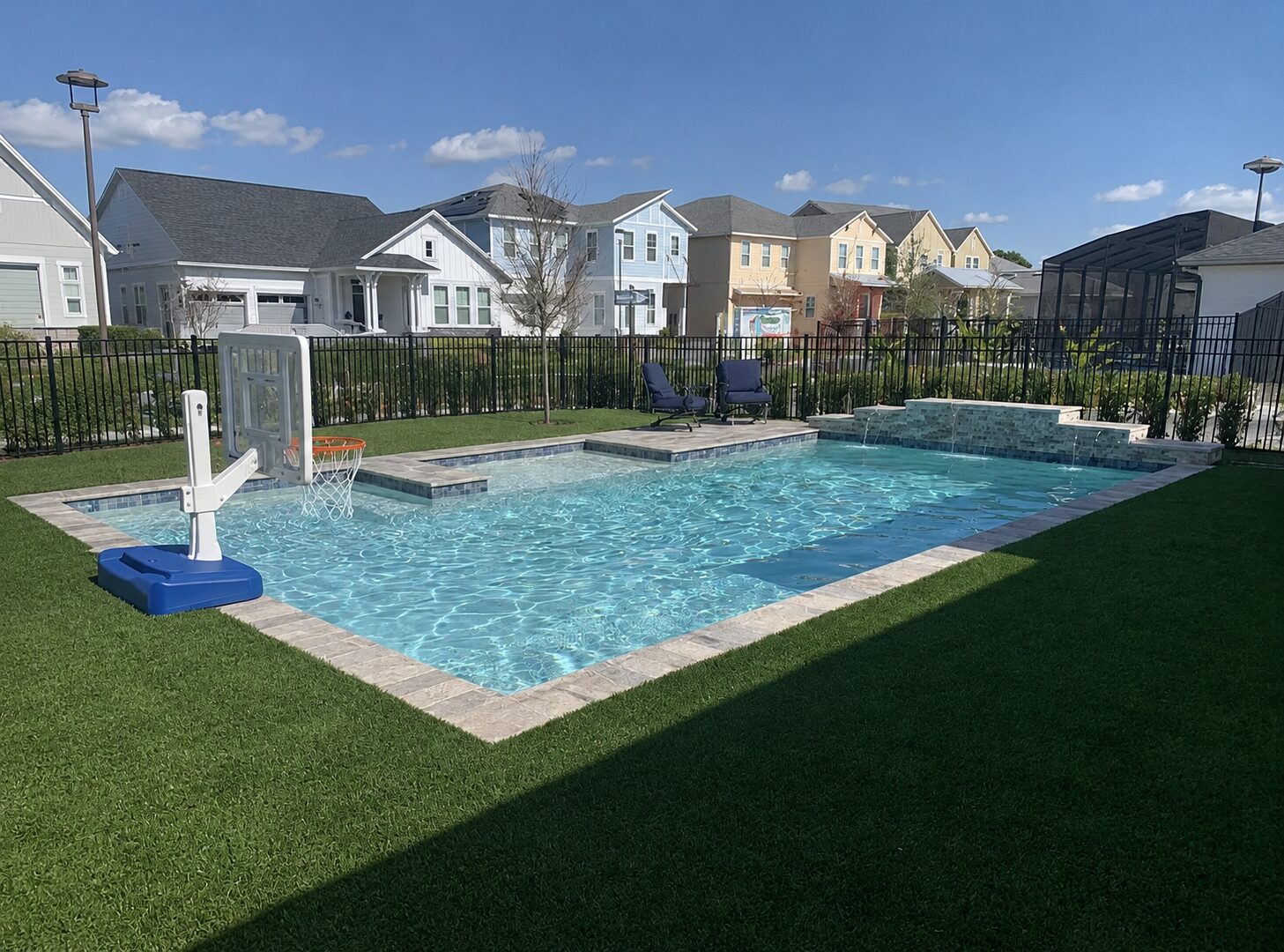 Pool with deep blue water, scupper wall feature, and poolside seating