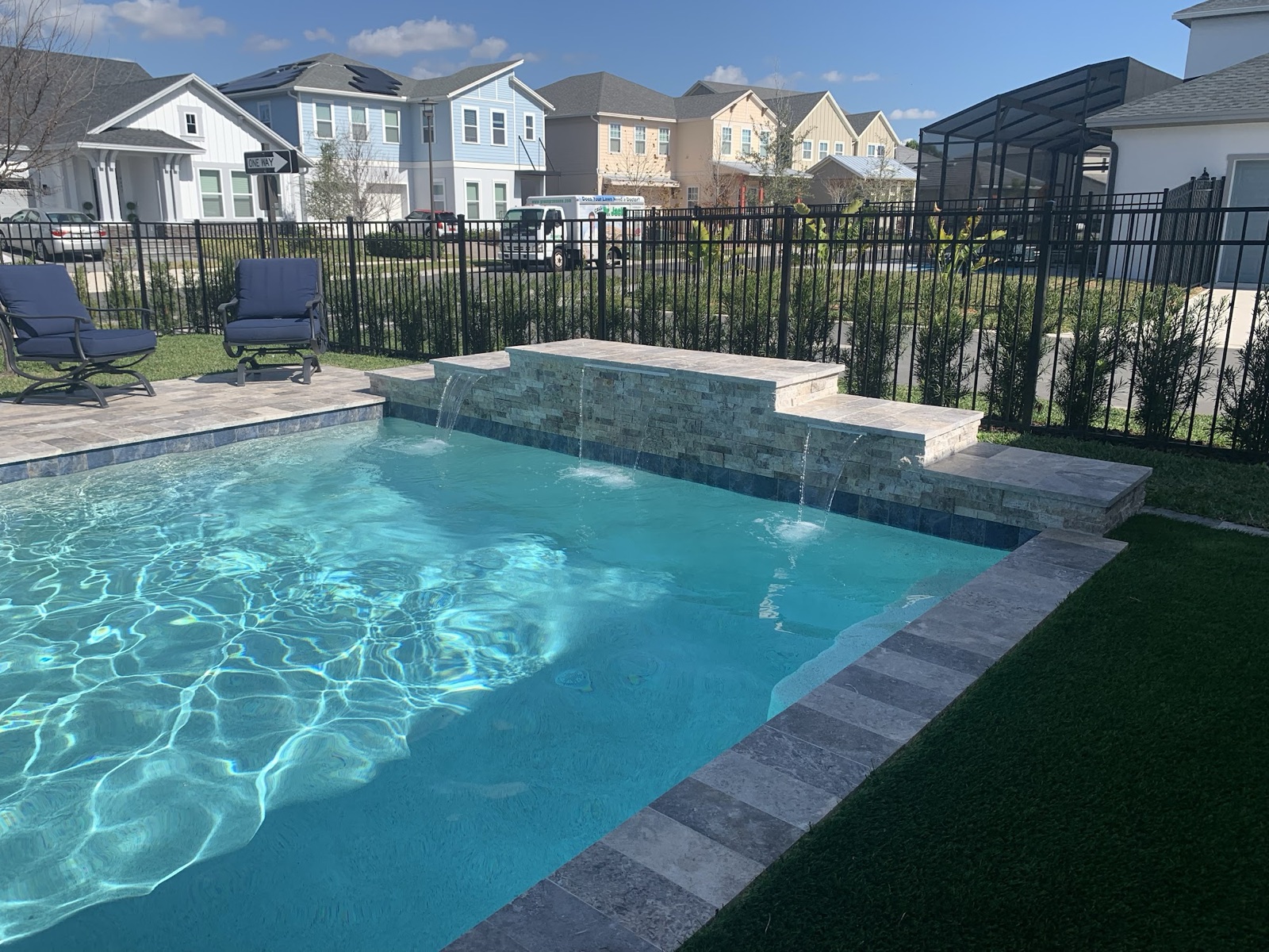 Rectangular pool with raised spa and sheet-waterfall spillover behind a Central Florida home